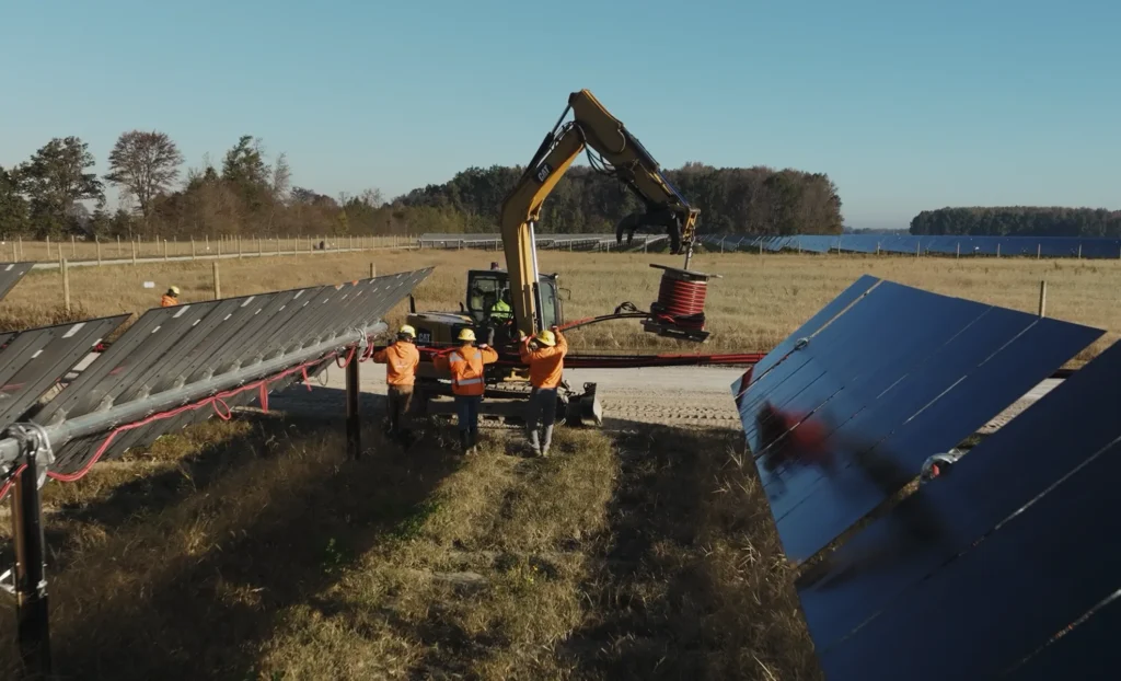 Photo of a construction vehicle working between a rows of solar arrays.
